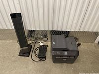 Side view showing the black tower fan with remote and Brother MFC printer side-by-side