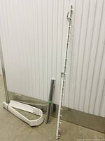 White shade screen roller tube and rod leaning against wall with white window blind slats and headrail on floor.