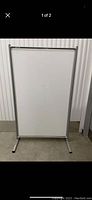 Whiteboard shown standing upright on flat legs against wall, with silver frame and blank white dry-erase surface.