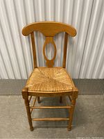 Frontal view of wooden chair with curved backrest and woven seat