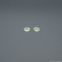 Two oval opal gemstones shown side by side on a dark background, showing color play.