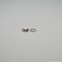 Two oval faceted Morganite gemstones on white background, showing pale pink color and size.