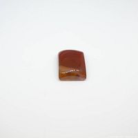 Polished rectangular carnelian gemstone with red and orange-brown hues on white background, showing surface and color details.