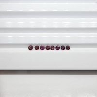 Ten small round pink tourmaline gemstones laid out in a single row on a white surface.