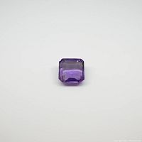 Square cut purple amethyst gemstone against a plain background, showing top view and angles.