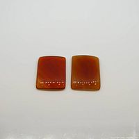 Top view of two square cabochon carnelian gemstones placed side by side on a white background.