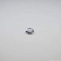 Close-up image of the natural oval aquamarine gemstone on a neutral background.