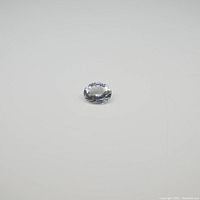 Top and angled views of a single loose oval aquamarine gemstone showing its clarity, cut, and light blue color on a plain white background.