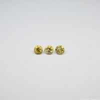 Three round yellow citrine gemstones laid side by side showing their top facets