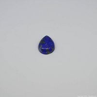 Pear-shaped lapis lazuli gemstone from front view on plain white background, showing blue color with some matrix inclusions.