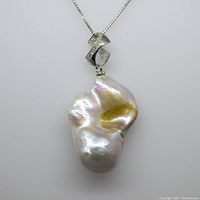 Front view of baroque pearl pendant with decorative sterling silver bail and attached chain.