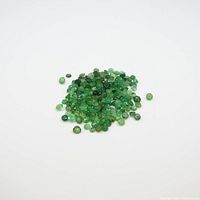 Pile of small faceted round green gemstones on white background