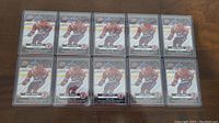 Ten identical Cole Caufield rookie hockey cards in protective cases laid out on a flat surface.
