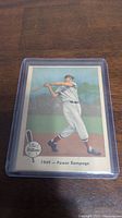 Front view of 1959 Fleer Ted Williams baseball card in protective case, showing illustration of Ted Williams swinging a bat with label '1949 - Power Rampage'.
