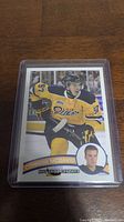 Front of Connor McDavid hockey card showing him in Erie Otters uniform with card details, protected in plastic sleeve.