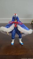 Front view of WWE Blue Blazer action figure in blue wrestling outfit and blue cape with white faux fur trim.