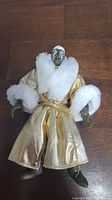 Front view of WWE Goldust action figure showing detailed face paint and gold robe with white fur collar and cuffs.