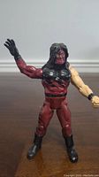 Front view of WWE Kane action figure showing red and flesh tone arms, detailed muscle sculpt and flame body paint, black gloves and boots.