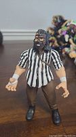 Front view of WWE Mankind action figure showing striped shirt, mask, and arm accessories.