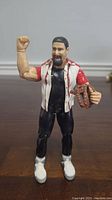 Front view of the WWE Mick Foley action figure standing with right arm raised and holding a brown spiked accessory.