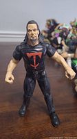 Front view of WWE Undertaker action figure showing detailed face, hair, and black t-shirt with red 'T' logo.