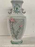 Full front view of white porcelain vase with lattice pattern and pink floral relief, green painted accents on rim and base, two decorative handles on neck