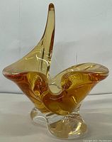 Front left angled view of amber and clear chalet art glass sculpture with elongated upward extension and flowing base