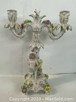 Full view of Dresden porcelain candle holder showing two candle arms, floral detailing, and child figurine base with chip damage and hand missing
