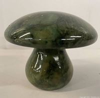 Front view showing glossily polished green stone mushroom sculpture with natural veining.