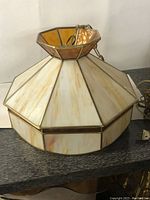 Front and side view of stained glass hanging lamp showing cream and amber glass panels and metal framing