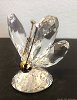 Front view of the Swarovski crystal butterfly showing faceted crystal wings, gold-tone metal head with black eye detail, and crystal-topped antennae on faceted crystal base.