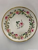 Top view of the round vintage porcelain plate showing floral design and gold edge trim.