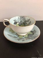 Tea cup and saucer set showing cup with handle and floral design on saucer and cup exterior.