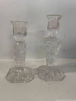 Two crystal candle holders side by side with decorative cut patterns, showing full height and design details.