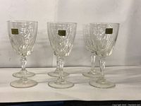 Front view of six Luminarc crystal champagne glasses lined up, showing the etched pattern and gold Luminarc label stickers on the bowls.