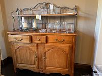 Full front view of the Ethan Allen buffet with metal rack holding glassware and candles