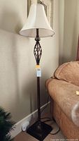 Full view of metal floor lamp showing entire lamp next to a sofa.