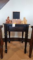 Full front view of the small wooden game table with drawer, featuring wooden chess pieces on top and a wooden box.