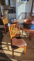 Group shot of chairs around a table showing wood finish and seat padding