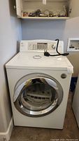 Front view of LG dryer showing porthole door and top control panel with power cord on top