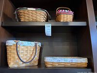 Four Longaberger baskets on a shelf; two on top and two below with fabric liners and natural wood weave.