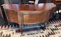 Front view of semi-circular wooden desk showing carved molding and fluted legs