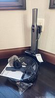 Shark Ion handheld vacuum on charging dock with robot vacuum and accessories laid on floor next to a wall outlet.