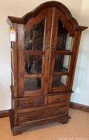 Front view showing overall piece with glass doors and drawers