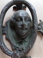 Close-up of the front face of the door knocker showing Shakespeare's detailed relief portrait and oval frame.