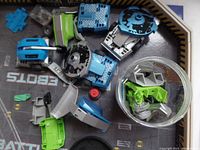 Close up of assorted Hex Battlebots plastic robot pieces and components in blue, green, black, silver and gray colors.