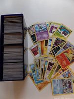 Stack of Pokemon cards fanned out showing variety of types including Fire, Water, Psychic, and Darkness.