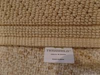 Close-up photo showing the tag of the bath mat indicating Threshold brand, quality & design, and made in India.