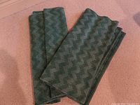 Two folded green chenille cotton runners showing the chevron pattern on a carpeted floor.