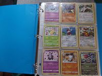 Photo of an open binder page showing nine Pokemon cards in clear plastic pockets